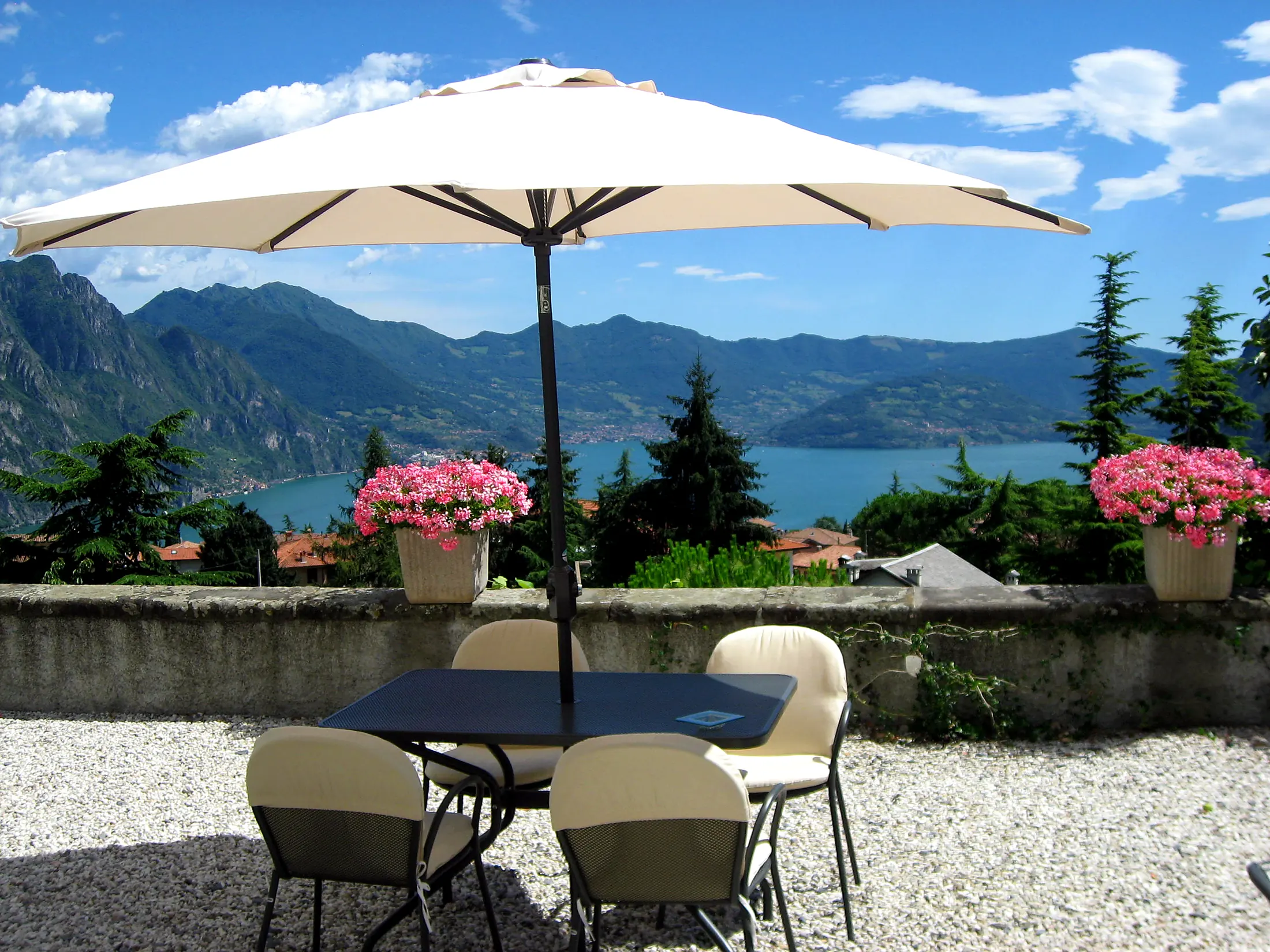 The sun terrace with a parasol, flowers and the lake